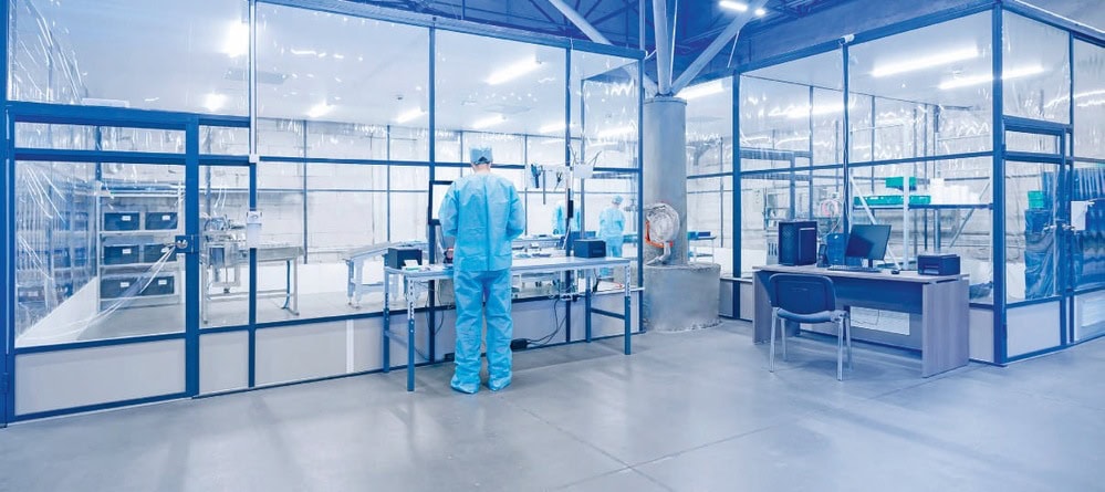 Laboratoire récent avec personnel en tenue de protection, espace moderne et sécurisé pour la recherche ou la fabrication de produits pharmaceutiques ou biotechnologiques.