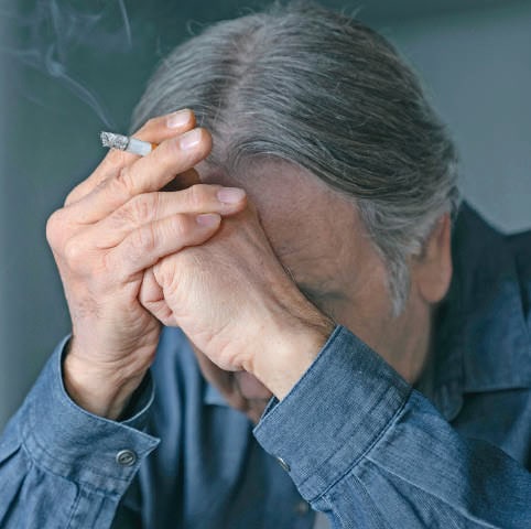 Homme âgé avec douleur oculaire, tenant sa tête dans ses mains, montrant un inconfort lié à une opération ou un problème de santé des yeux.
