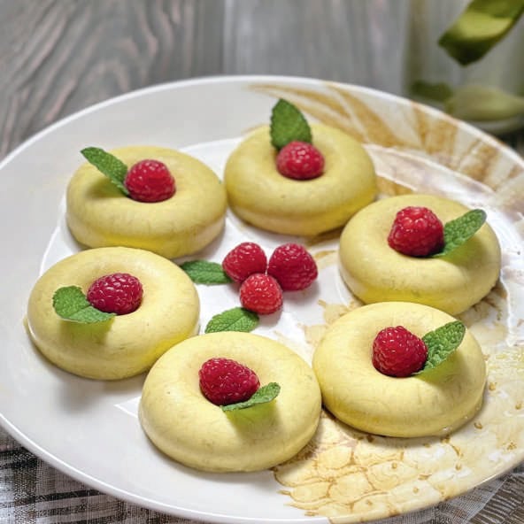 Pâtisseries aux framboises fraîches et feuilles de menthe, présentées sur une assiette blanche, parfaites pour une alimentation saine et gourmande.