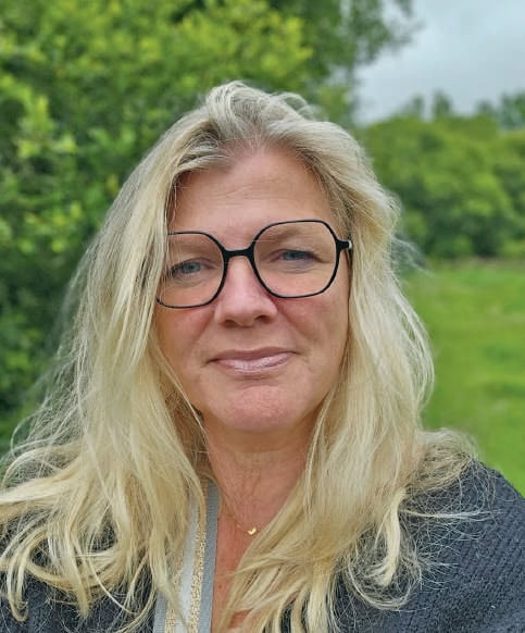 Femme avec lunettes, souriant légèrement, en extérieur avec verdure, illustrant le sujet des étourdissements posturaux-perceptifs persistants (PPPD).