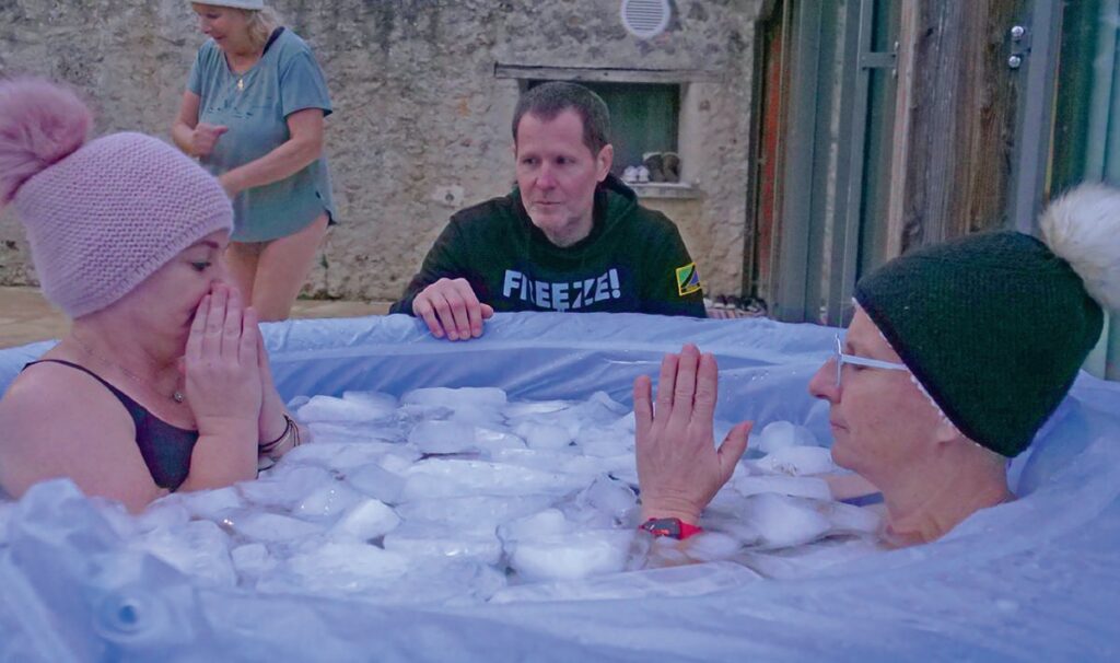 Personne âgée et jeune participant à une séance de bain de glace pour la récupération musculaire, encadrée par un professionnel dans un environnement extérieur.